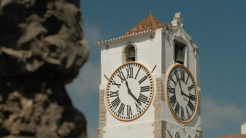 White clock tower behind blurred stone.
