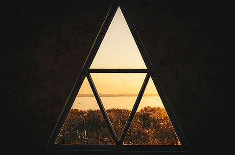 Triangular window framing a sunset.