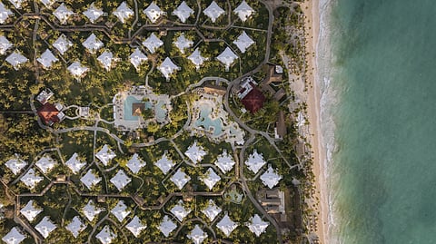 Aerial photograph of a large beachfront resort with pools, palm trees and white sand