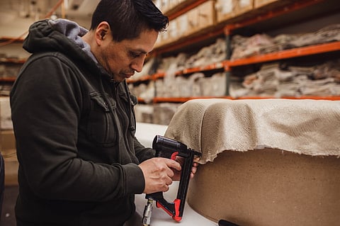 An Eastern Accents craftsman stapling fabric onto an upholstered piece
