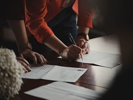 Hands signing a document.