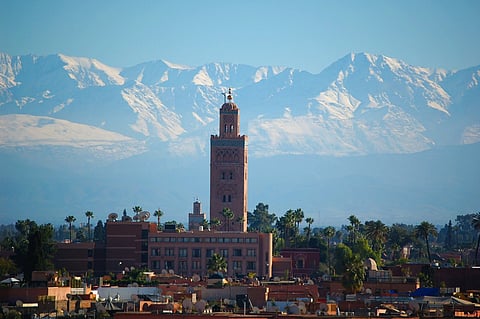 Mosque minaret against snow-capped mountains.