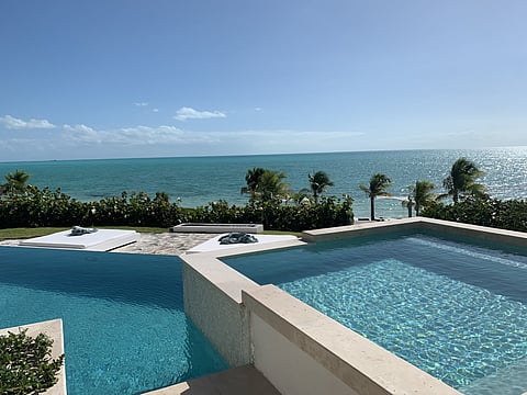 Infinity pool and terrace of a private villa overlooking turquoise sea and palm trees
