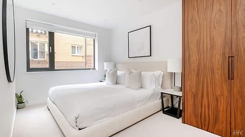Modern white bedroom with a wooden wardrobe.