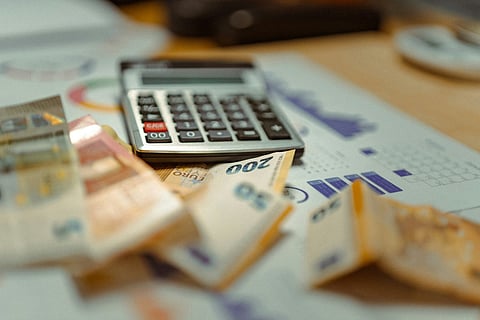 Euro banknotes and a calculator on financial charts.