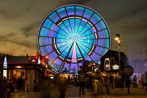 Illuminated Ferris wheel at an amusement park at night.