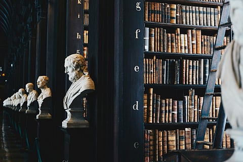 Library bookshelves lined with antique books and classical busts.