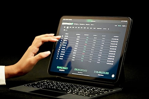 Person using a tablet showing trading charts and data.