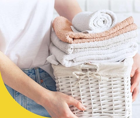 Person holding a basket of folded towels.