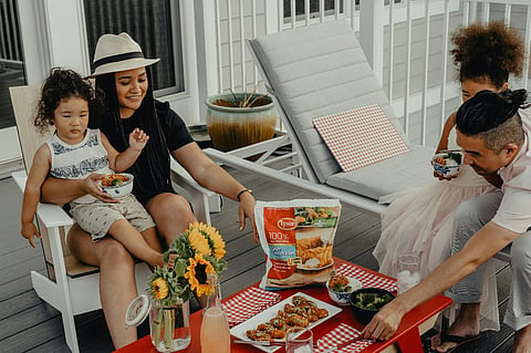 Family eating chicken strips on an outdoor patio.