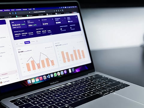 MacBook Pro displaying a financial dashboard with charts.