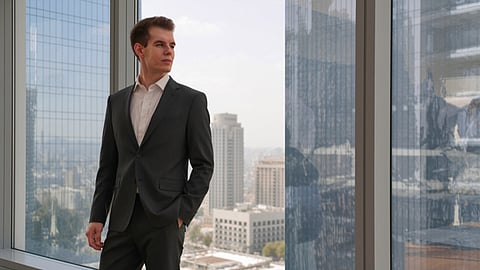 Man in a suit standing by a window.