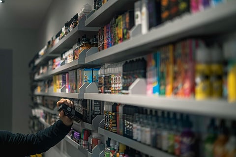 Hand reaching for a product on vape shop shelves.