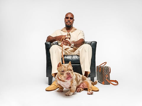 Demetrius A. Matthews seated in a leather chair with a merle bulldog at his feet