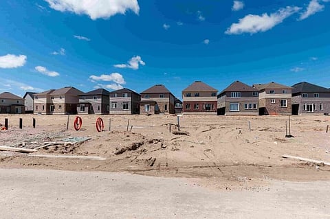 New suburban houses under construction behind dirt lots.