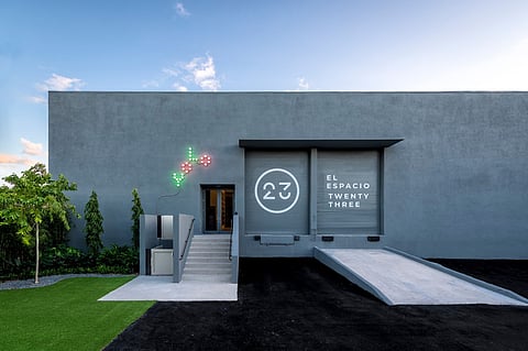 Gray concrete art building with a 23 logo, a ramp and a green lawn under a blue sky