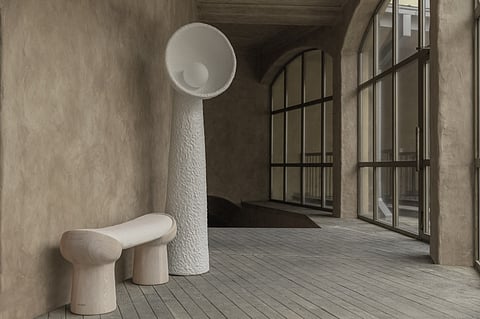 Sculptural floor lamps with dish-shaped shades and a low bench in a stone-walled room