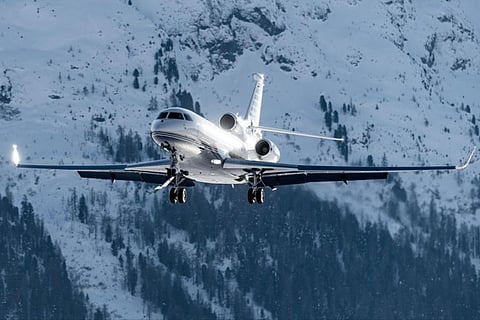 Private jet flying near snowy mountains.