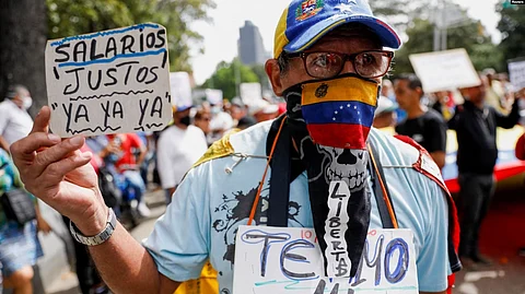متظاهر فنزويلي يرفع لافتة تتطالب بتحسين الأجور