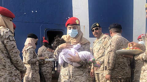 مجندة بالقوات البحرية تحمل طفلاً قادم من السودان