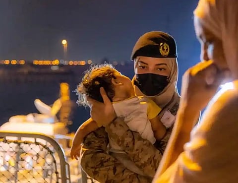 مجندة بالقوات البحرية تحمل طفلاً قادم من السودان