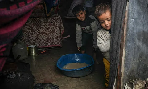 طفلان فلسطينيان في خيمة أغرقت أرضها مياه الأمطار