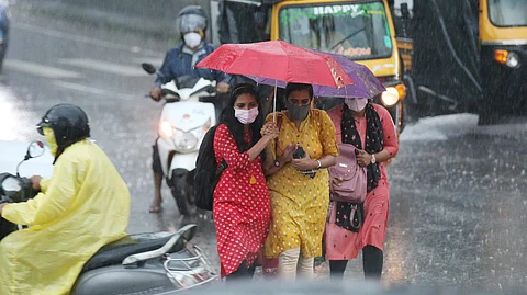 three girls in one umbrella during rainy day in kerala