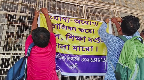 नौकरी गंवाने वाले टीचरों ने डीआई कार्यालय के सामने बैनर लगाकर कर विरोध प्रदर्शन करते हुए