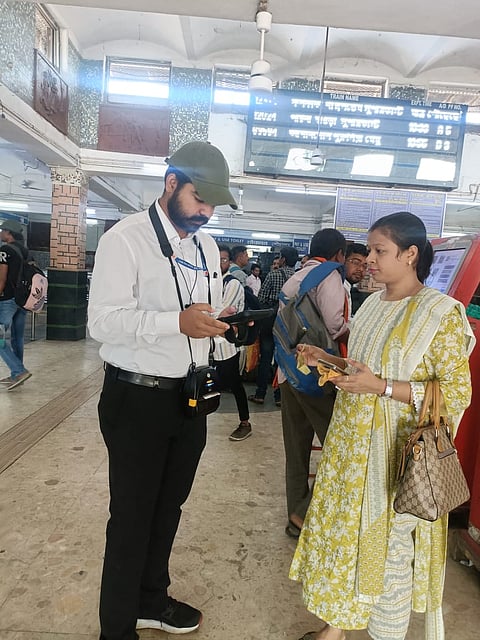 यात्री को मोबाइल अनारक्षित टिकटिंग सिस्टम समझाते अधिकारी