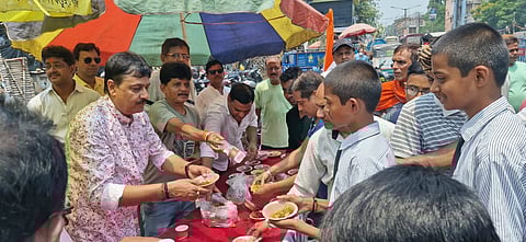 राहगीरों को पानी का बोतल और जलेबी देते अमरनाथ चटर्जी