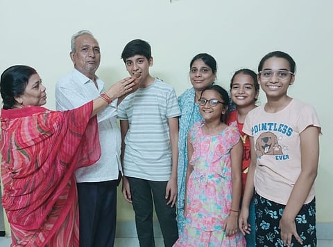 मिठाई खिलाते नमन के परिजन