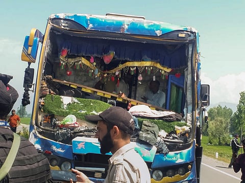 दुर्घटनाग्रस्त एक बस के पास खड़े सुरक्षाकर्मी