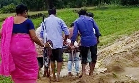 सड़क की हालत खराब होने से खाट पर मरीज को ले जाया जा रहा