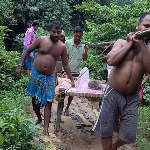 सड़क की हालत खराब होने की वजह से रोगी को खटिया पर लिटा कर ले जाया जा रहा अस्पताल