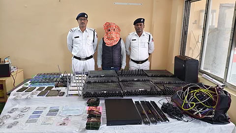 गिरफ्तार अभियुक्त के साथ जब्त अवैध सिम बॉक्स को दिखाते हुए पुलिस कर्मी