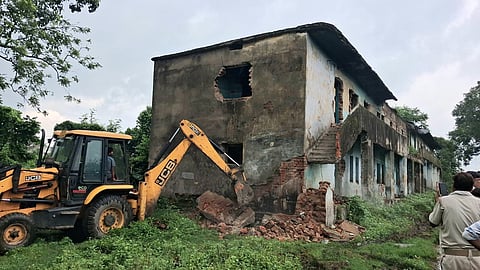 अवैध रूप से कब्जा किये गये क्वार्टरों को ध्वस्त करता जेसीबी मशीन