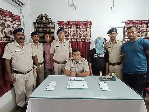 पुलिस अधिकारी गिरफ्तार अभियुक्त को दिखाते हुए