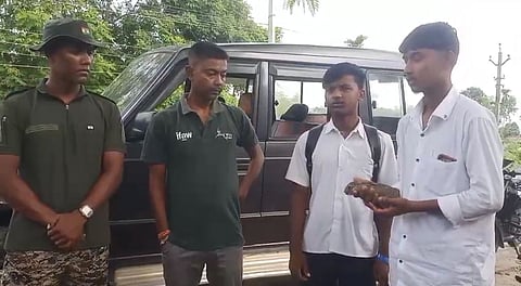 Image of two boys from Biswanath carrying the rescued the baby python