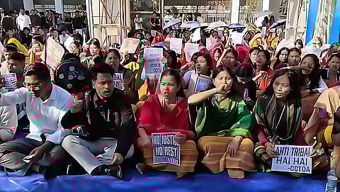 Image shows the students blocking the main entrance of Bodoland University at Debargaon and staging a sit-in demonstration