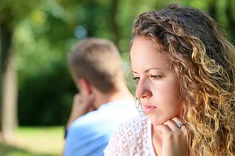 Sad young couple sitting on the bench at the park