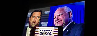 A dark room with two projected images of political figures on a screen—one man speaking on the left and another smiling on the right. In front, a smartphone displays a "2024 Presidential Election" graphic with patriotic colors and symbols, resting on a laptop keyboard.