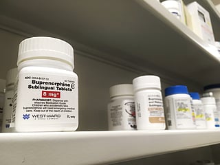 Buprenorphine bottle along with other medication bottles on a store or pharmacy shelf.