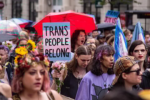 London, England, UK - July 8, 2023: London Trans+ Pride Protest. People march and chant while holding signs; a visible sign reads "Trans People Belong" and the sign is the colors of the Trans Pride flag.