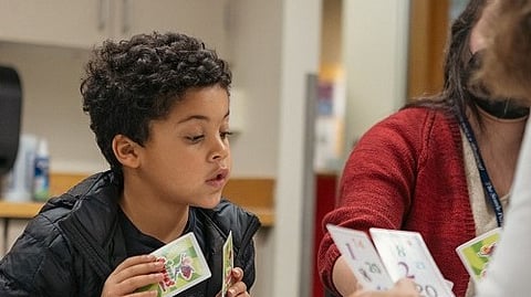 A child is working with arithmetic cards with two adults