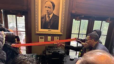 WSBLI CEO and President Kateesha Atterberry raises a pair of scissors to cut the ribbon at the Institute. People standing around the ribbon along the edges of the photo take photographs of the moment.
