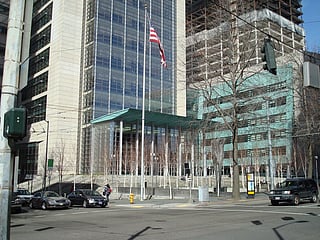 Street-view Image of a tall building with a U.S. flag on a flagpole in front of it.