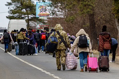 A Ukrainian border guard helps carry bags to refugees leaving the country through the Ukrainian–Slovak border.