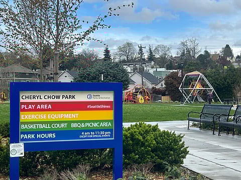 The park sign at the new Cheryl Chow Park, with play equipment visible in the background.