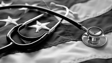 Black and white image of a stethoscope resting on a folded U.S. flag.