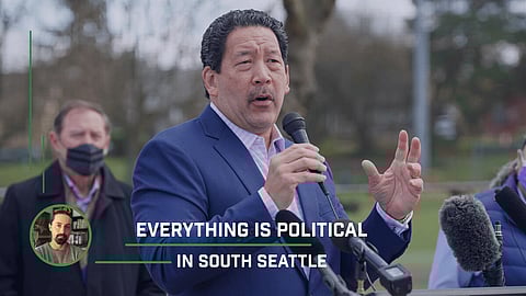 Bruce Harrell speaks at an outdoor press conference, gesturing while holding a microphone, with the caption “Everything Is Political in South Seattle” overlayed, highlighting local political tensions and community leadership.